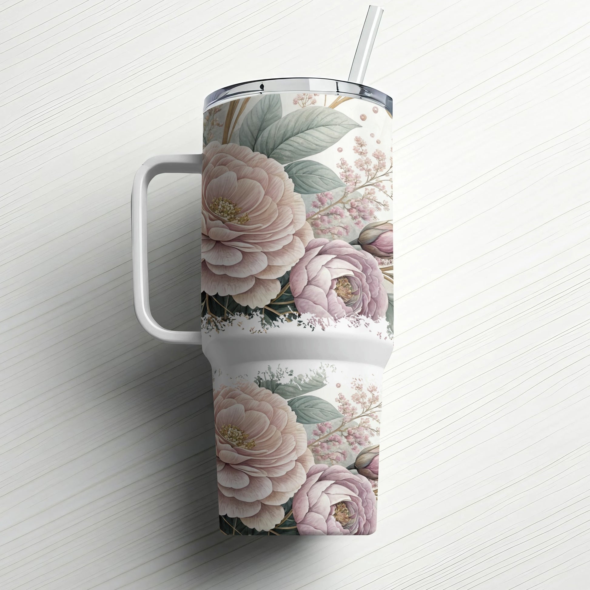 Floral patterned tumbler with handle and straw on white wooden background.