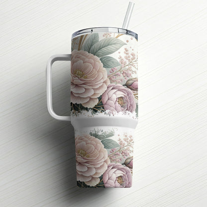 Floral patterned tumbler with handle and straw on white wooden background.