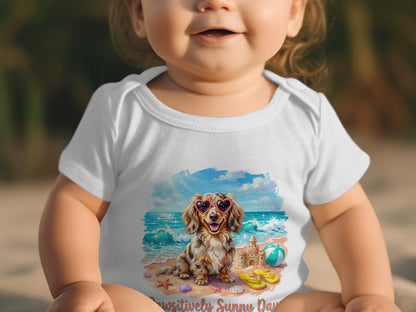 Baby in white bodysuit with dachshund beach graphic and "Pawsitively Sunny Day" text.