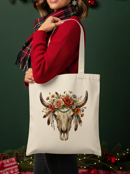 Cream tote bag with a bull skull design featuring flowers and feathers.