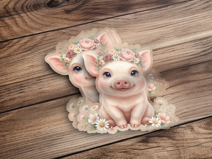 Two cute pigs wearing floral crowns, nestled among flowers on a wooden background.