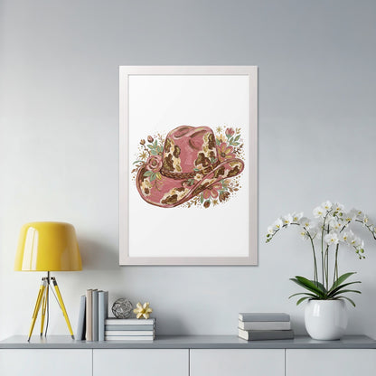Pink floral cowboy hat art print in a white frame on a shelf.