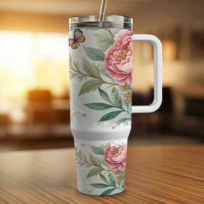 White tumbler with pink peonies and a butterfly on a wooden surface.