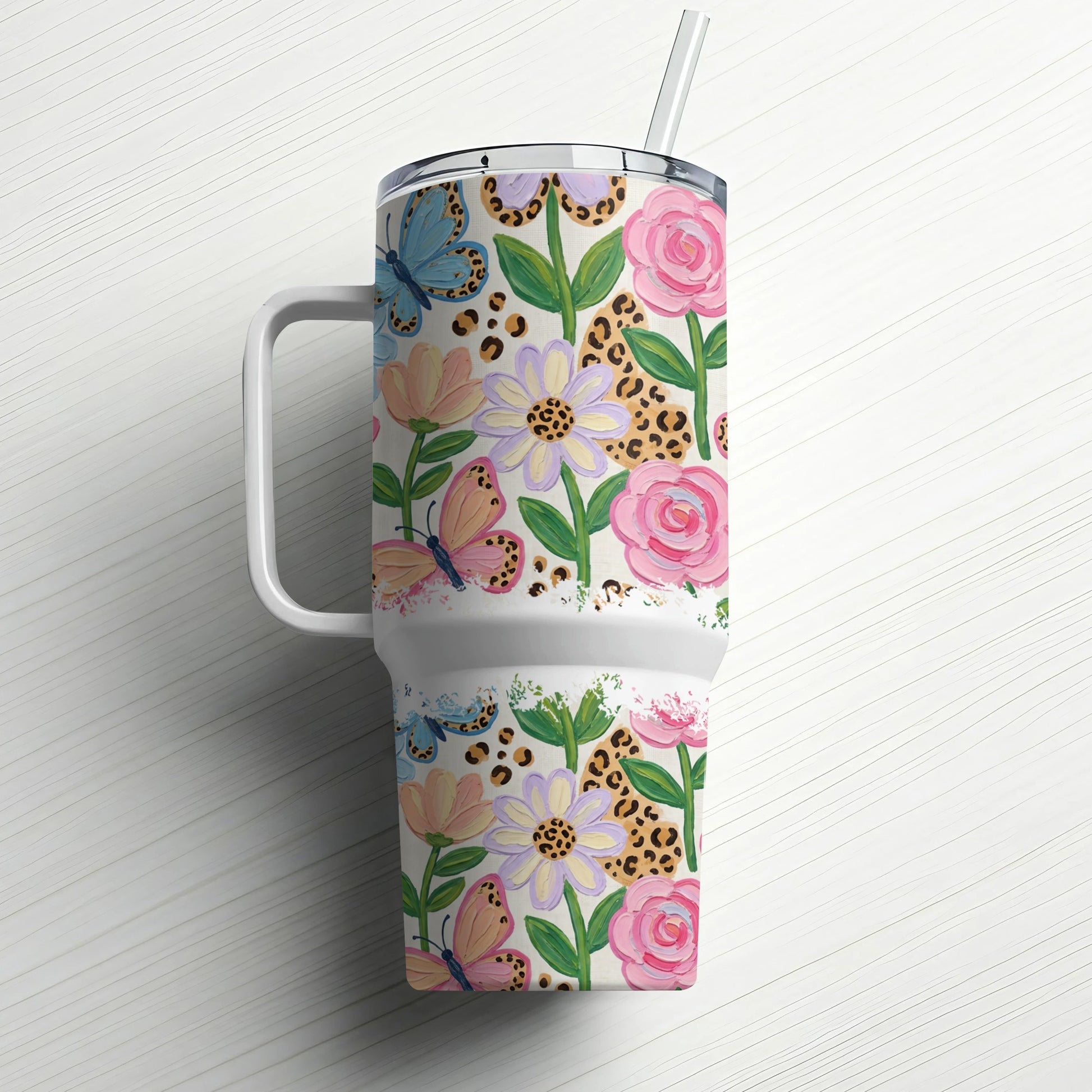 Floral and butterfly pattern tumbler with handle and straw.