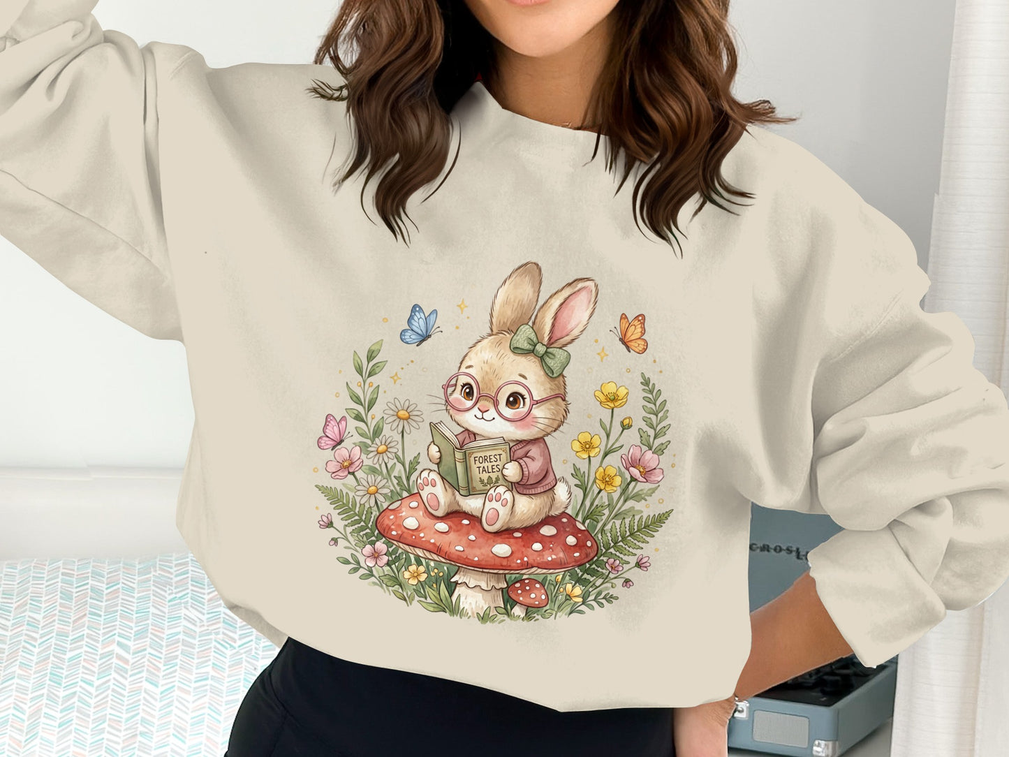 Woman wearing a sweatshirt with a cute bunny reading a book on a mushroom.