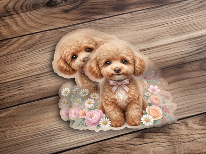 Two light brown toy poodles with pink bows surrounded by flowers.