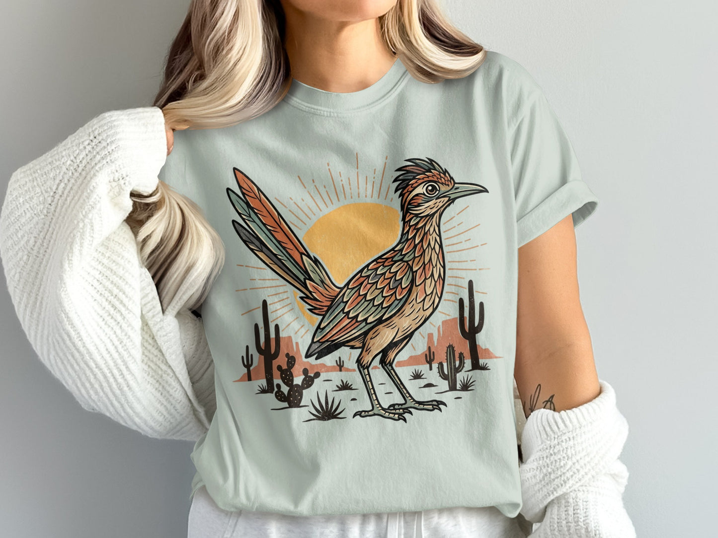 T-shirt with desert scene, sun, saguaro cacti, and roadrunner illustration.