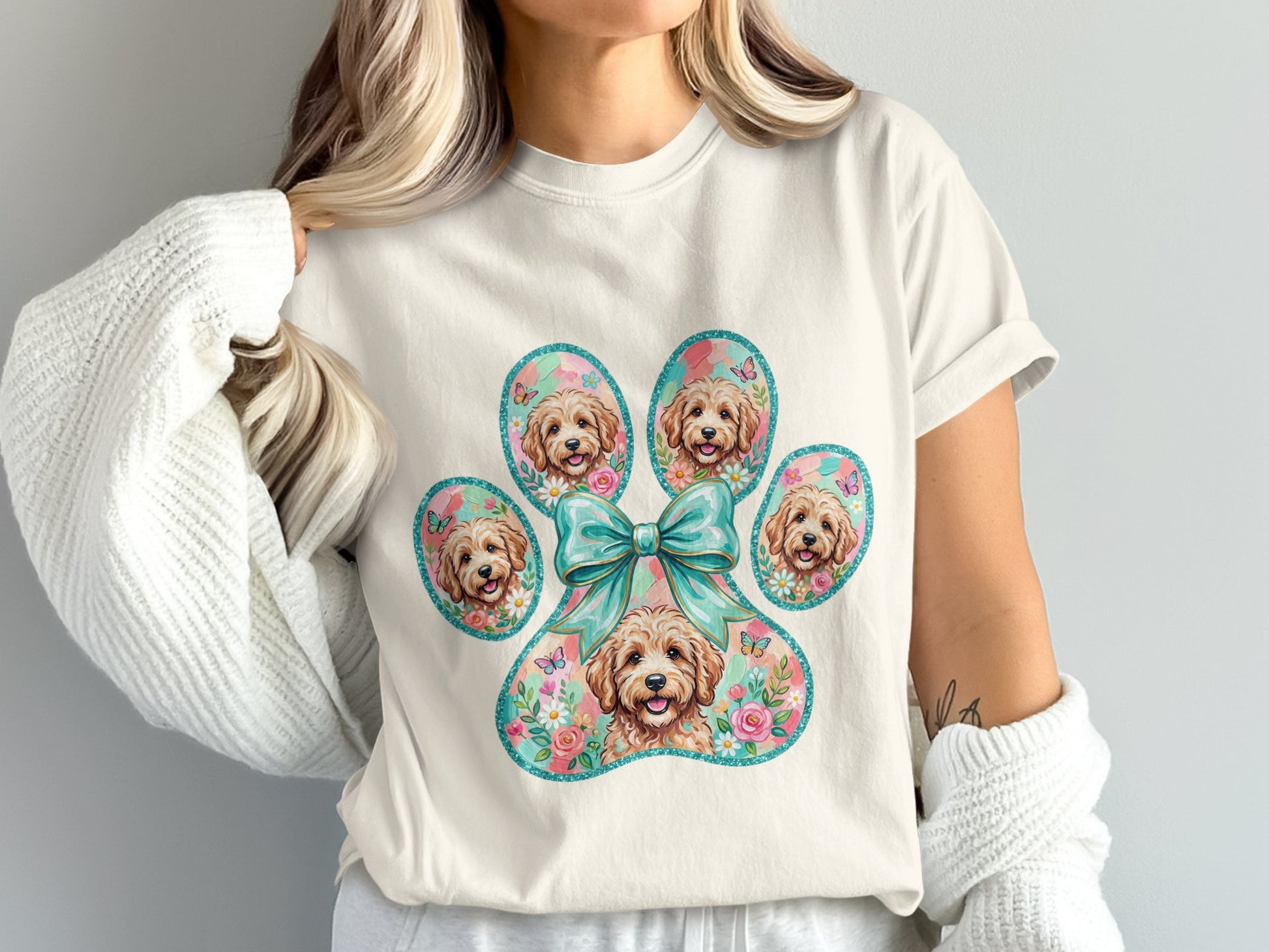 Cream t-shirt with a paw print filled with dog faces, flowers, and butterflies.