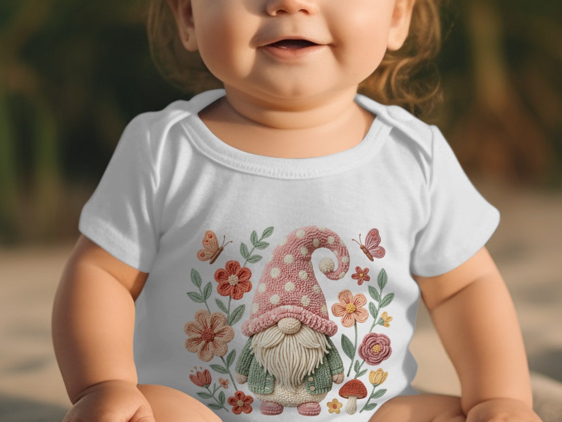 Baby in white onesie with gnome, flowers, and butterflies graphic.