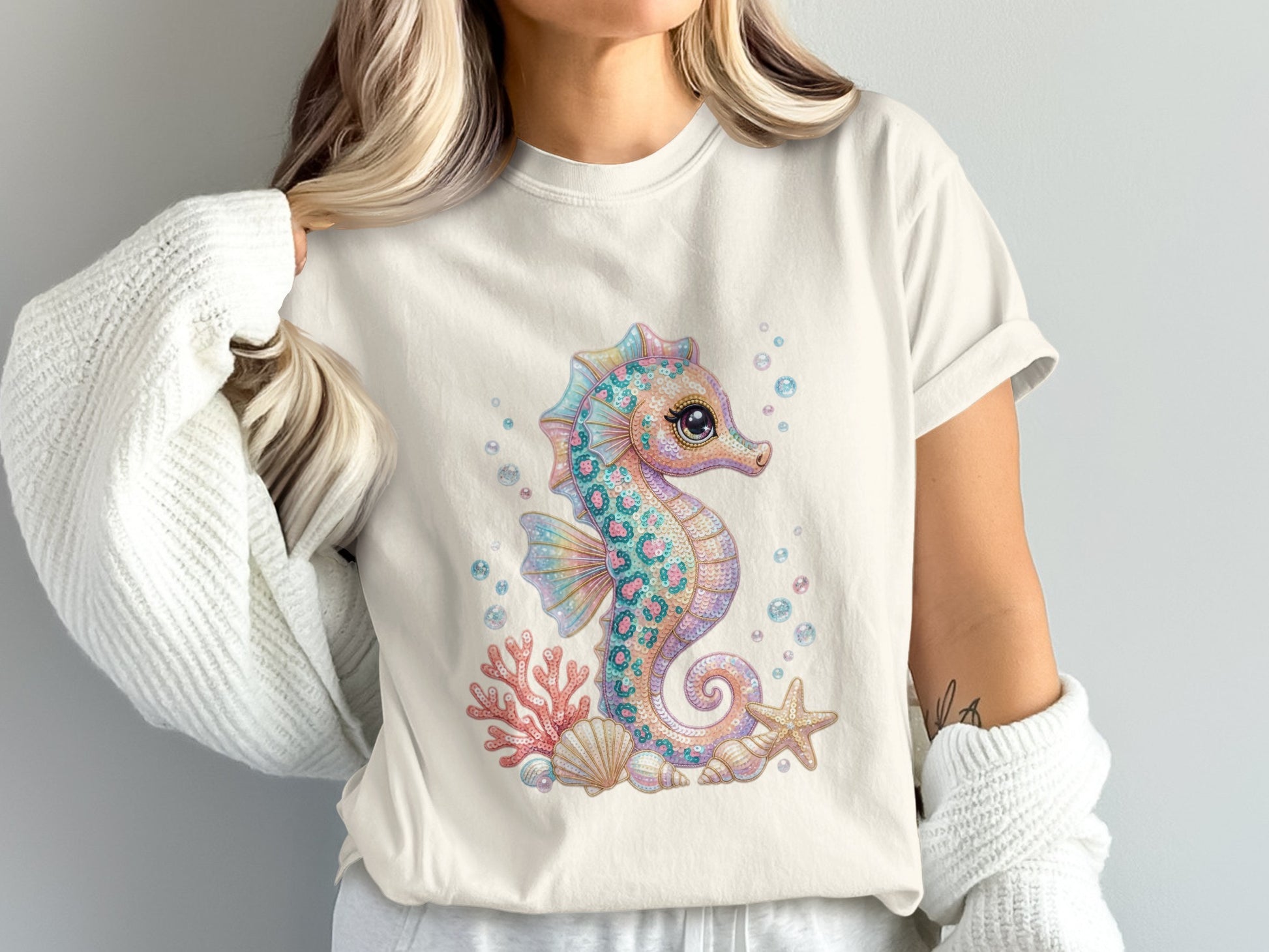 Seahorse graphic with seashells and starfish on a light-colored t-shirt.