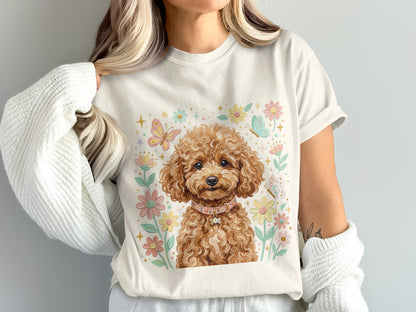 Cream t-shirt with a fluffy brown poodle wearing a pink collar surrounded by flowers and butterflies.