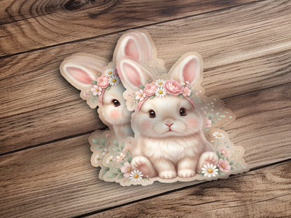 Two cute bunnies wearing floral headbands surrounded by flowers.
