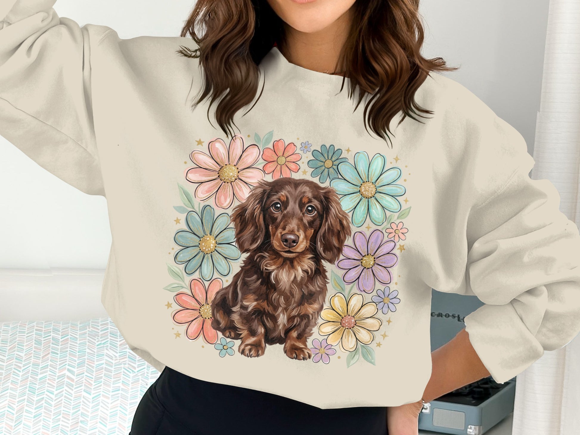 Dachshund wearing a floral wreath on a cream colored sweatshirt.