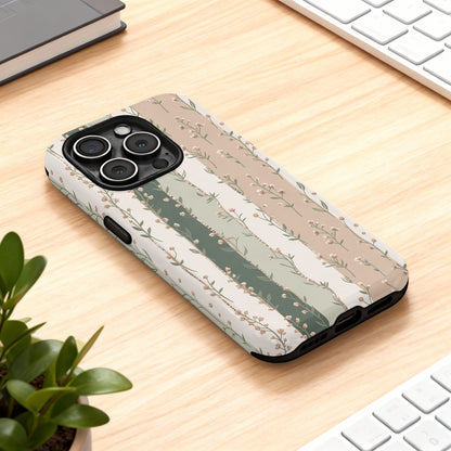 Floral striped iPhone case on a wooden desk with keyboard and plant.