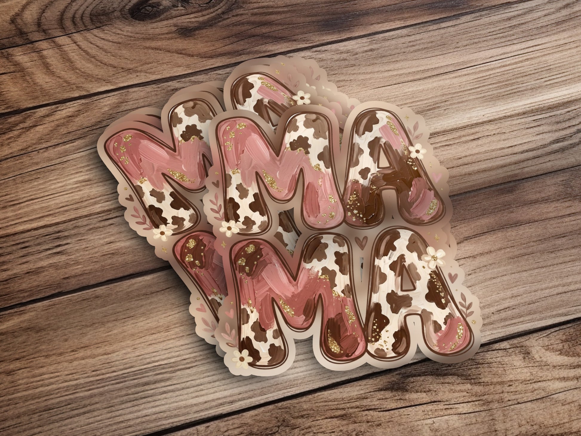 Brown and pink "Mama" lettering with cow print accents on a wooden background.