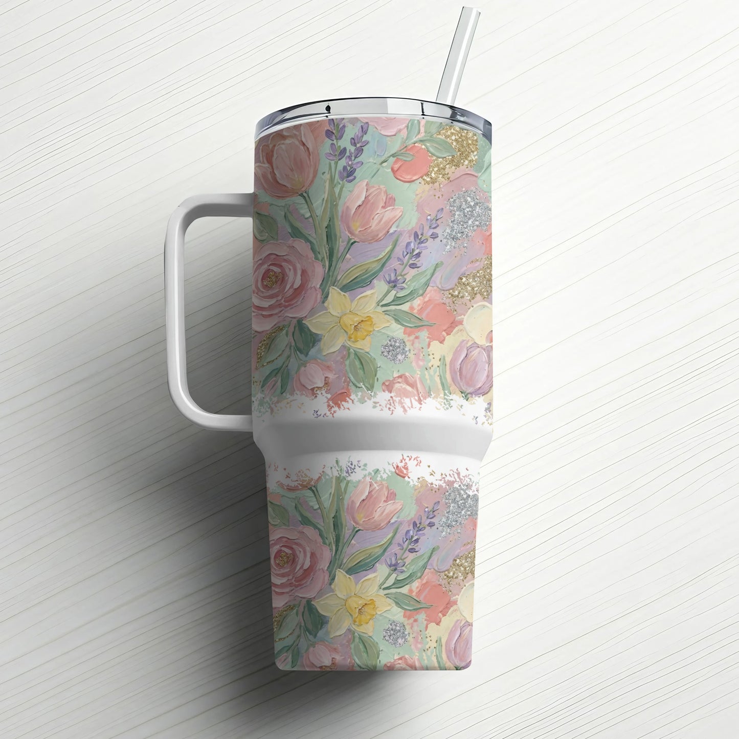 Floral patterned tumbler with straw on white wooden surface.