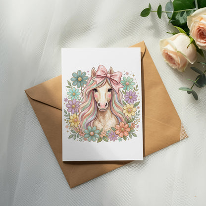 Illustration of a pink unicorn with a bow, surrounded by colorful flowers on a card.