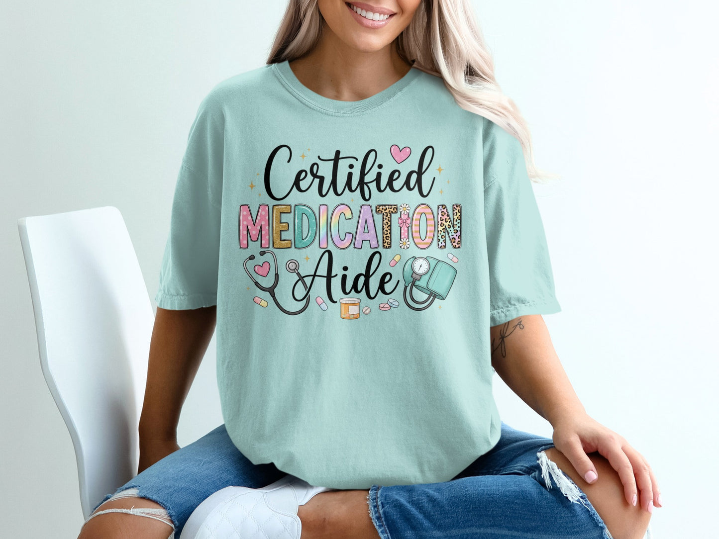 Mint t-shirt with "Certified Medication Aide" text and medical graphics.