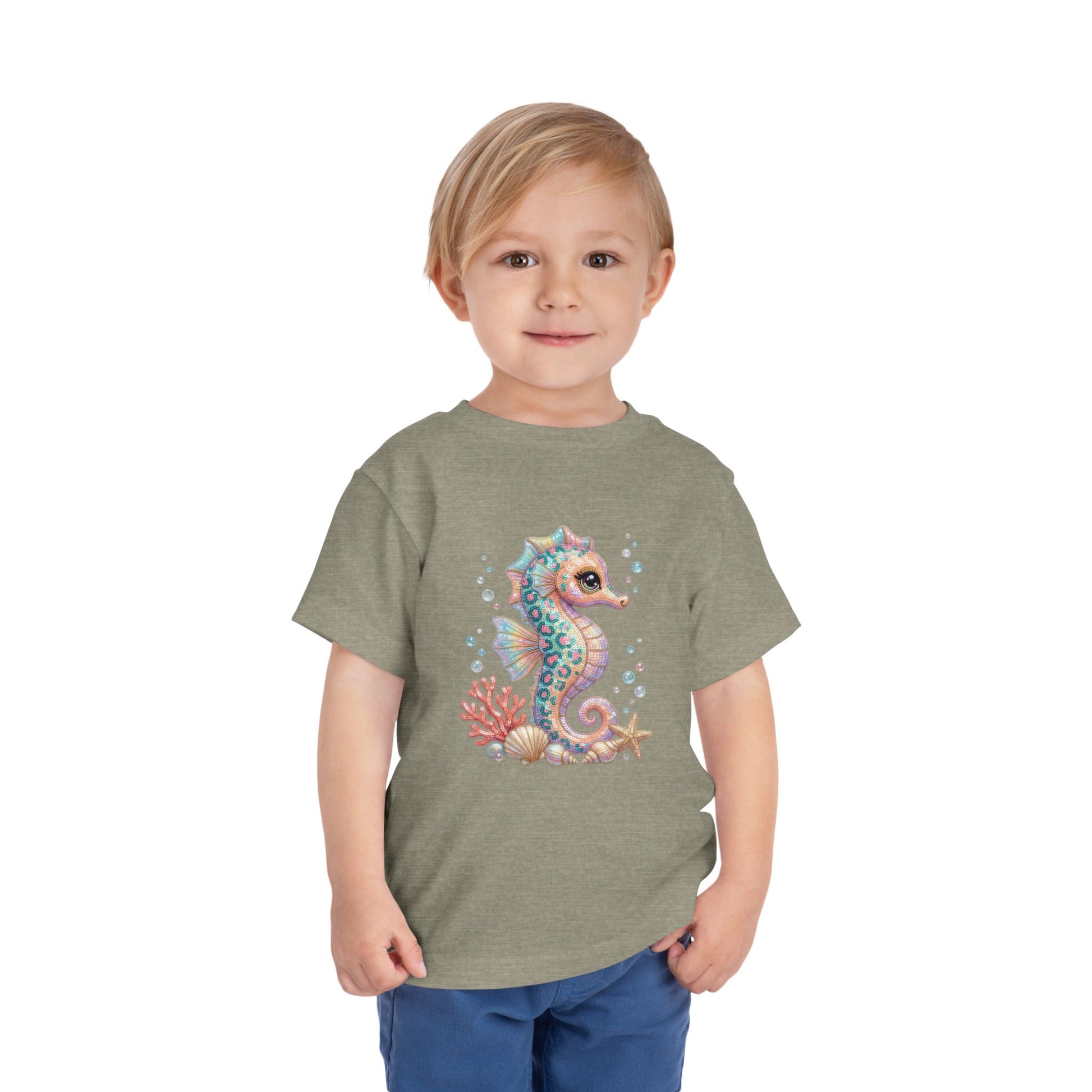 Child wearing a grey t-shirt with a colorful seahorse graphic.