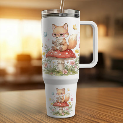 White tumbler with a cute fox reading on a mushroom, surrounded by butterflies and flowers.