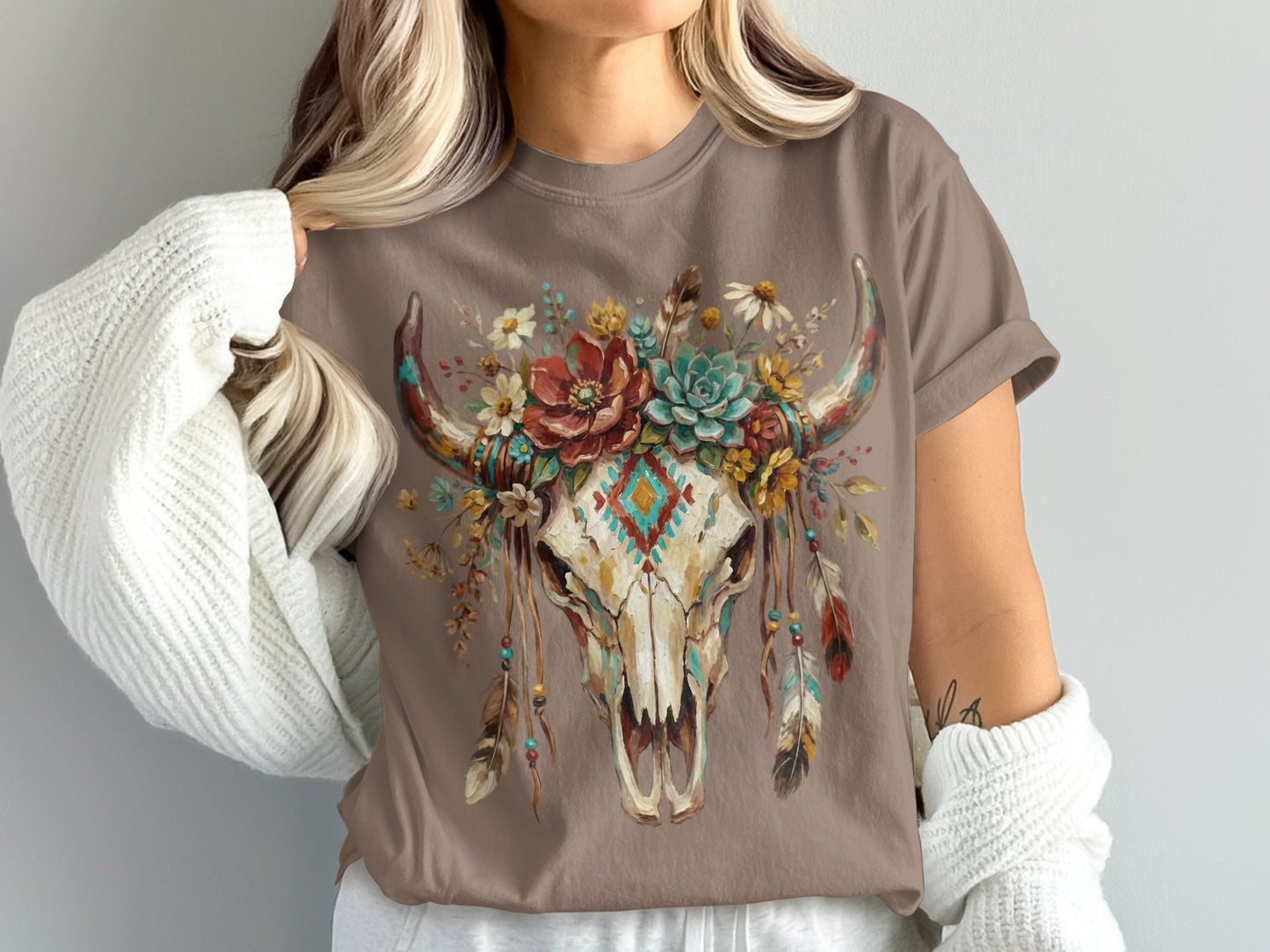 Brown t-shirt with a skull adorned with flowers, feathers, and a diamond pattern.