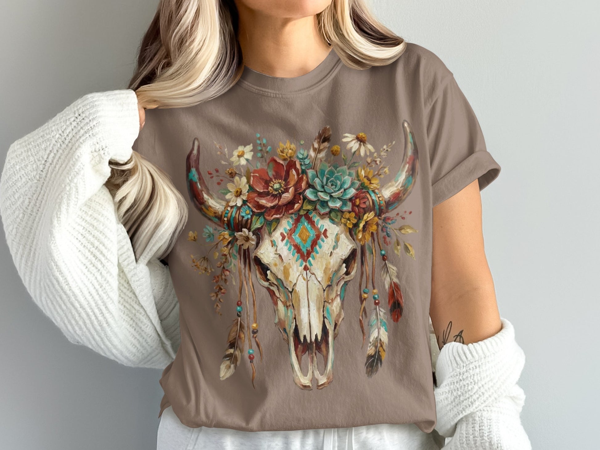 Brown t-shirt with a skull adorned with flowers, feathers, and a diamond pattern.