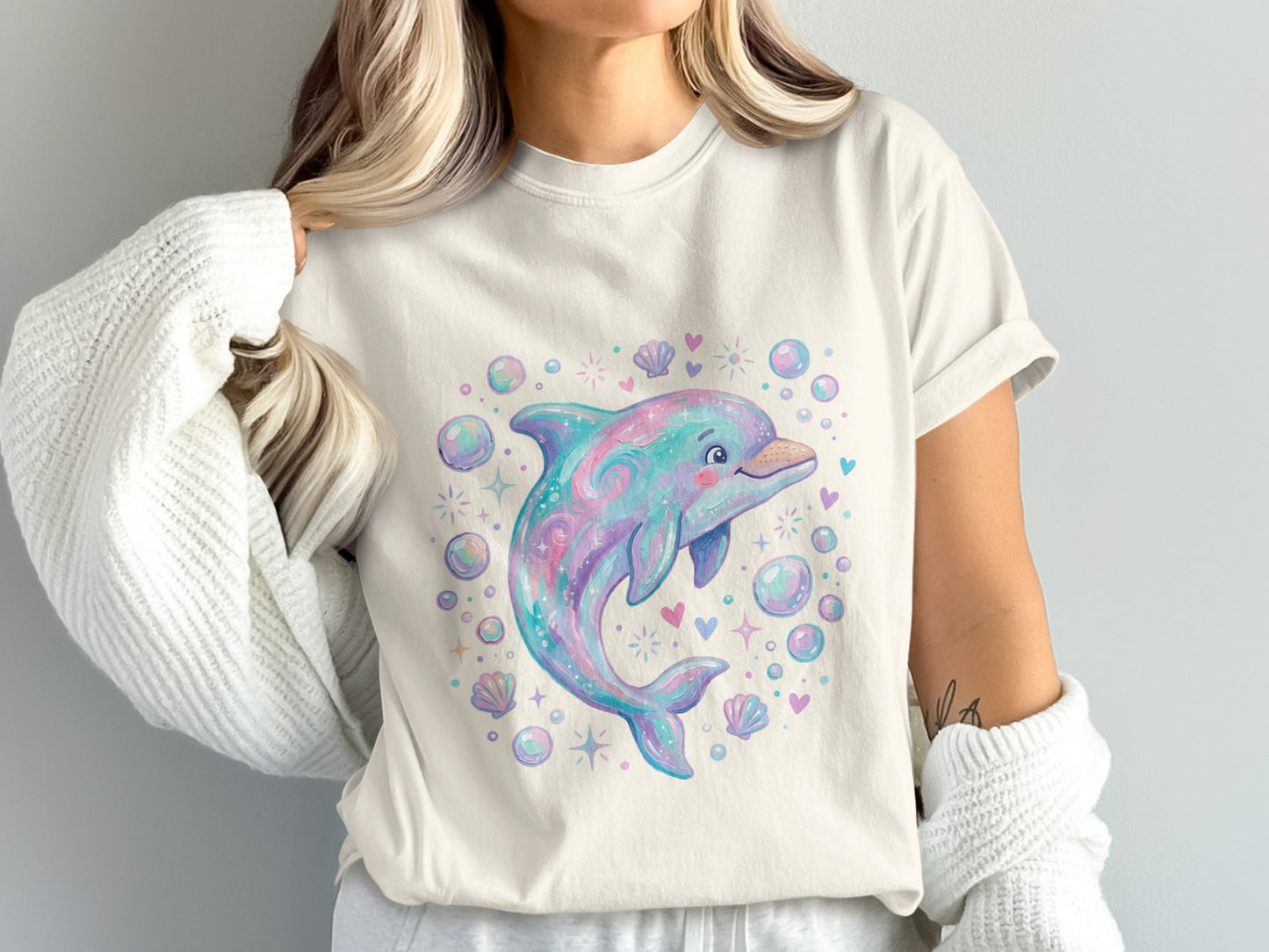 Pastel dolphin and seashells graphic on a cream t-shirt.