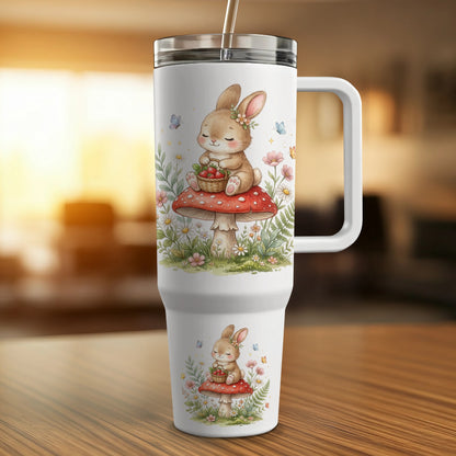 White tumbler with Easter bunny illustration on mushroom, surrounded by flowers.
