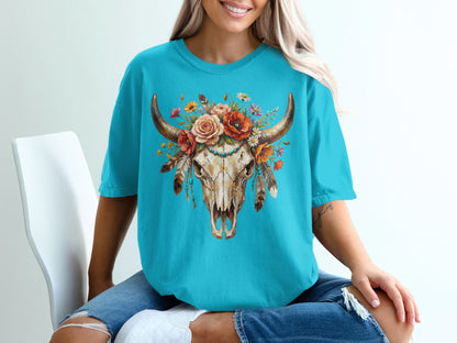 Turquoise t-shirt with a skull adorned with flowers and feathers.