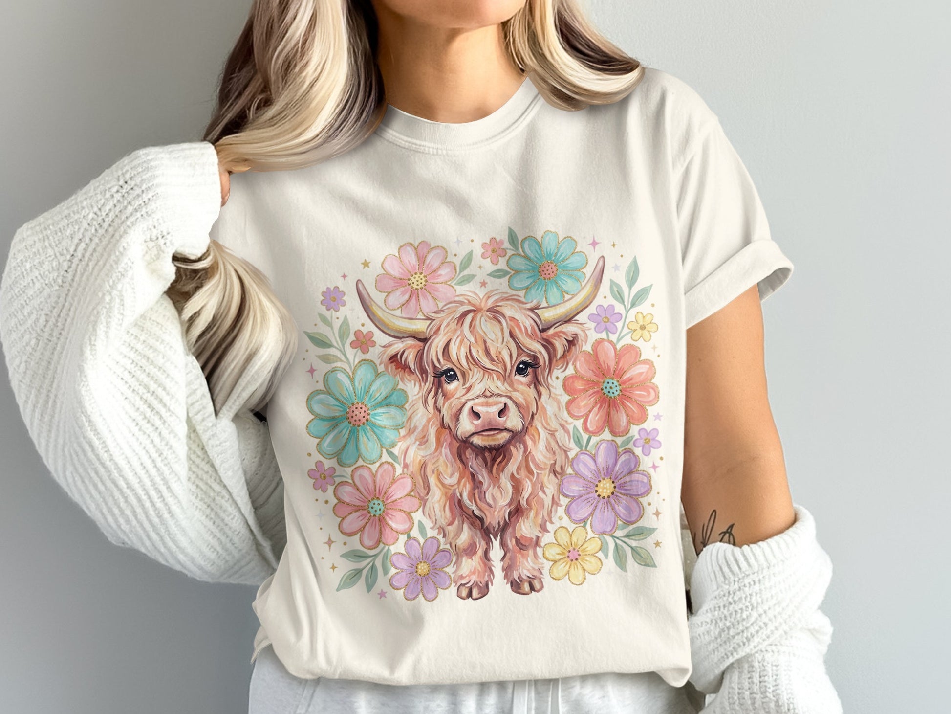 Cream t-shirt with a watercolor highland cow surrounded by pastel flowers.
