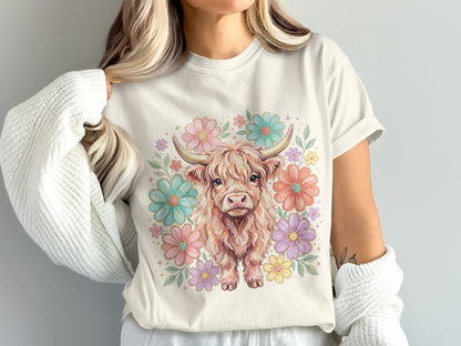 Cream t-shirt with a watercolor highland cow surrounded by pastel flowers.