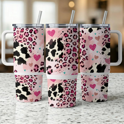 Three pink and black leopard print tumblers with hearts, on a counter.