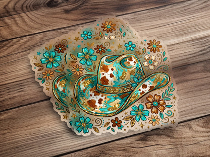 Cowboy hat with turquoise, gold, and floral accents on a wooden background.