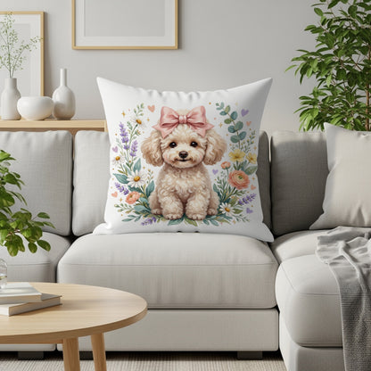 Fluffy white poodle puppy with pink bow sits amongst flowers on a pillow.