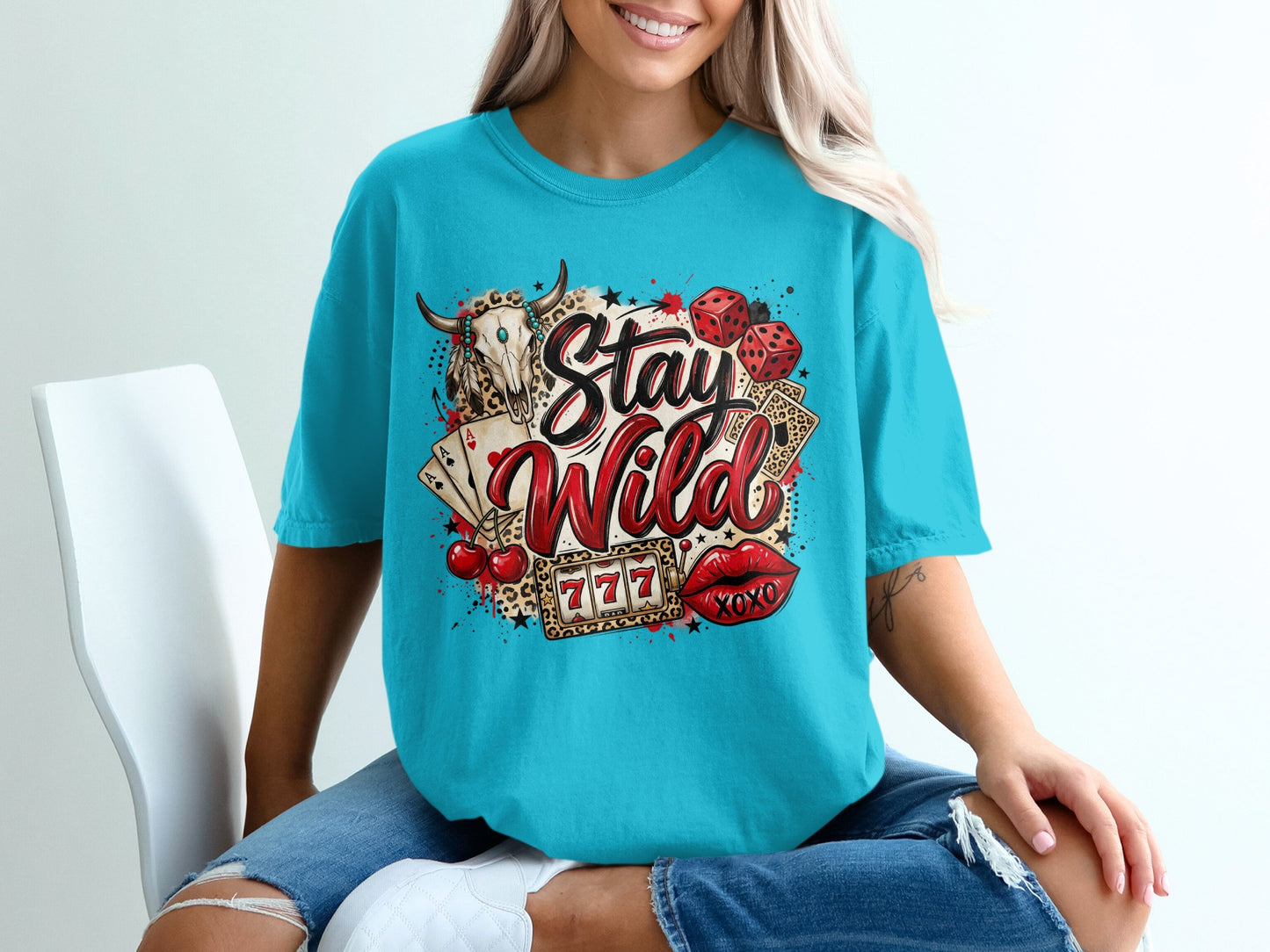Skull with bull horns, playing cards, dice, cherries, lips, and "Stay Wild" text on a t-shirt.