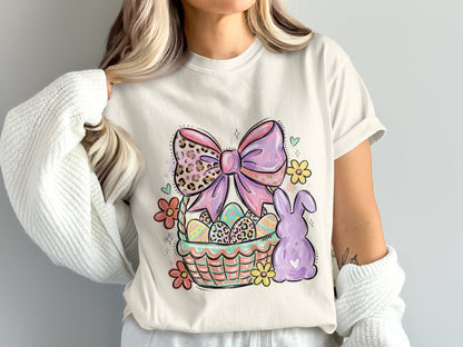 Easter basket with eggs, bow, and bunny graphic on a cream t-shirt.