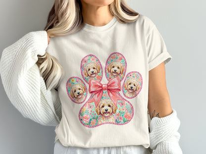 Cream t-shirt with a large pink paw print filled with small dogs and flowers.