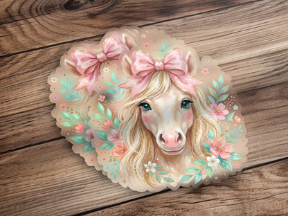 Whimsical horse with pink bows and floral accents on wood background.