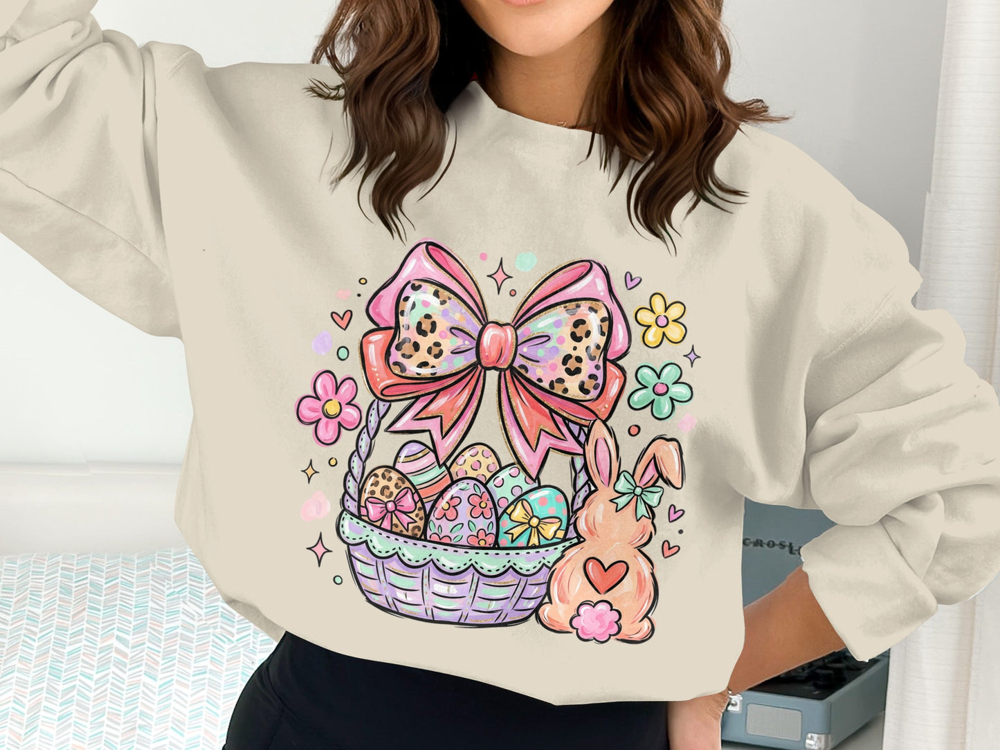 Easter basket with eggs, a bunny, and a pink bow on a cream sweatshirt.