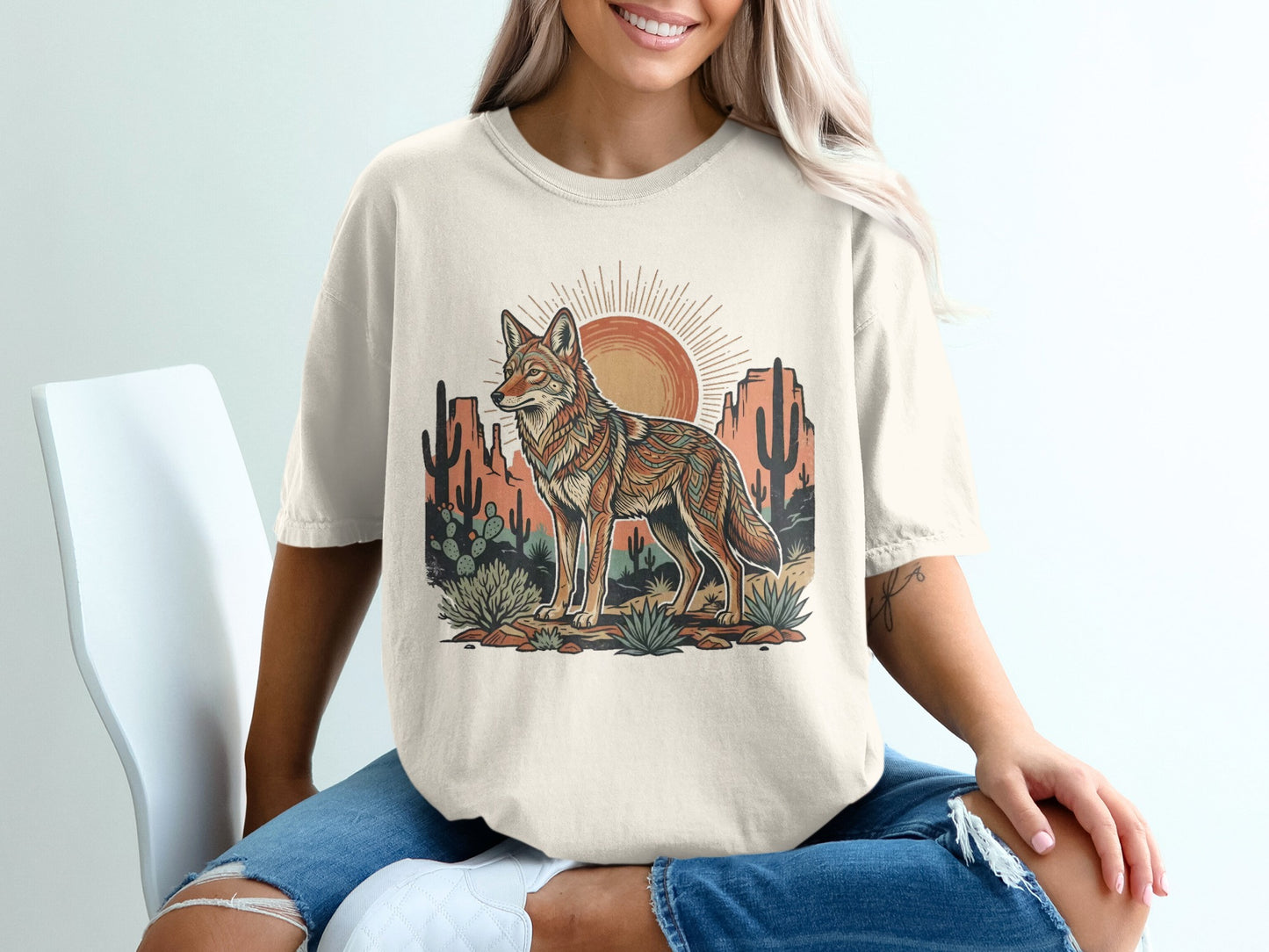 Coyote in desert landscape graphic on cream t-shirt.