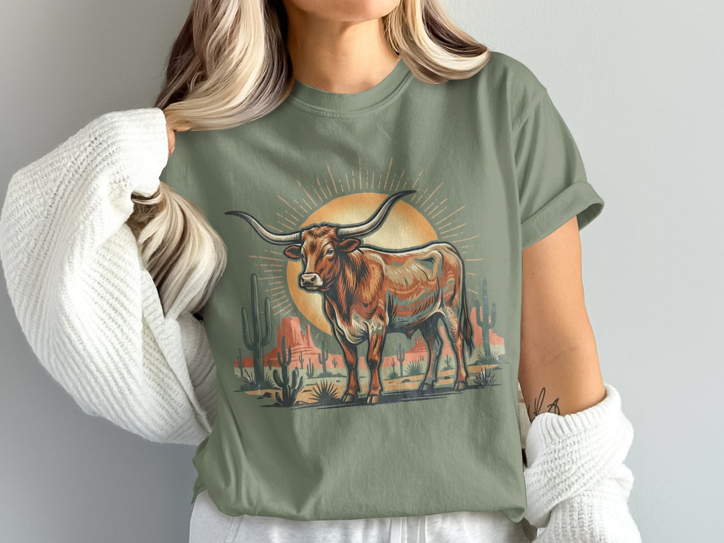 Longhorn bull standing in desert landscape with sunburst and cacti.