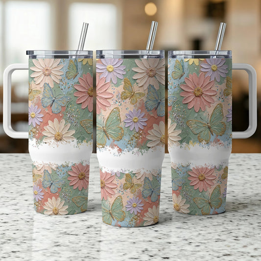 Three tumblers with butterfly and flower designs and white handles.