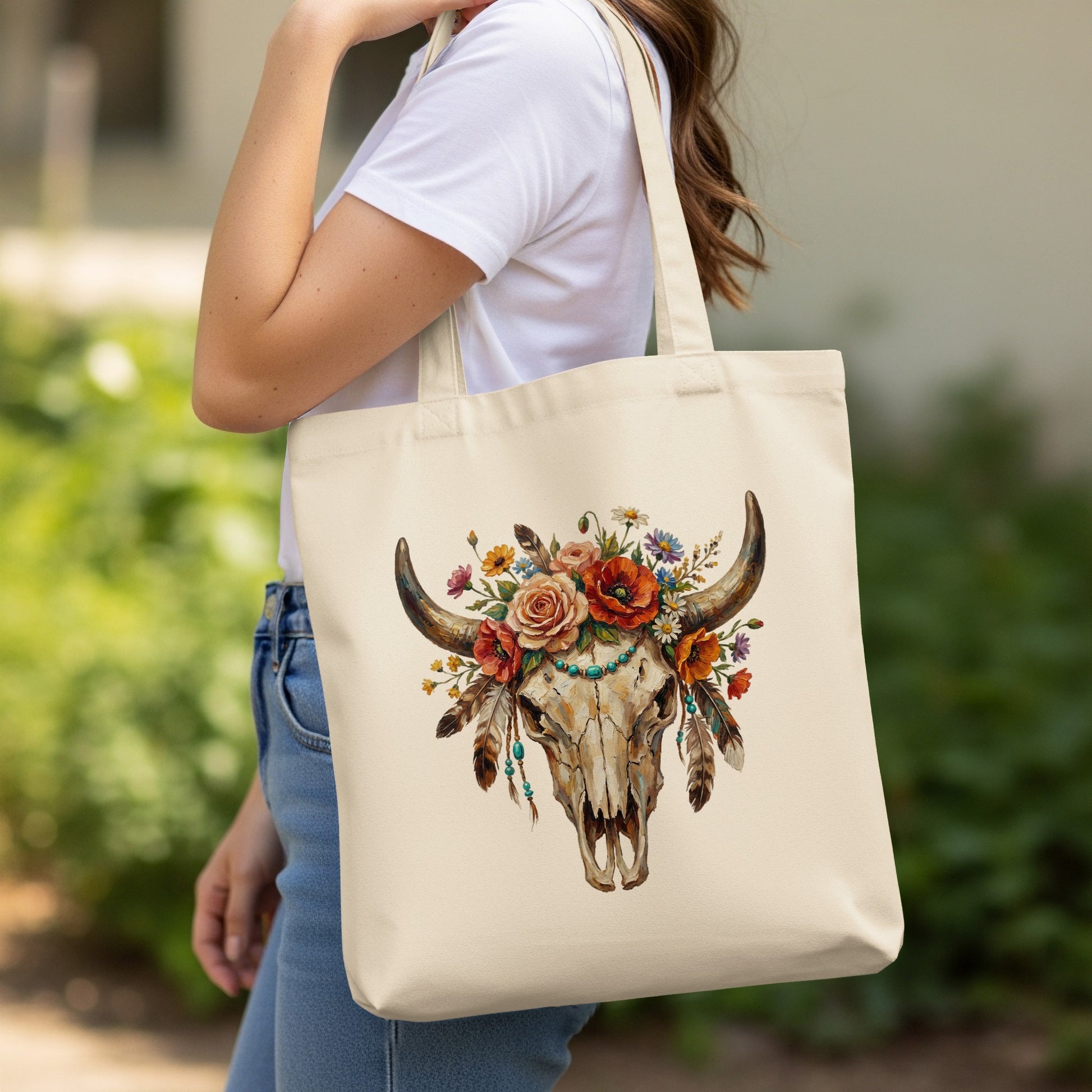 Canvas tote bag with a steer skull decorated with flowers and feathers.