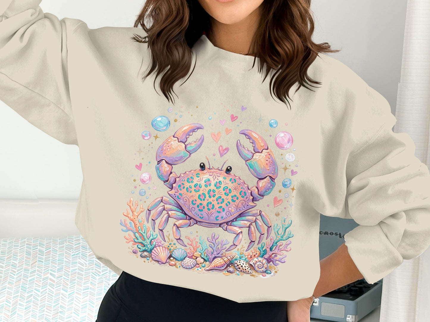 Crab graphic with seashells and coral on a cream sweatshirt.