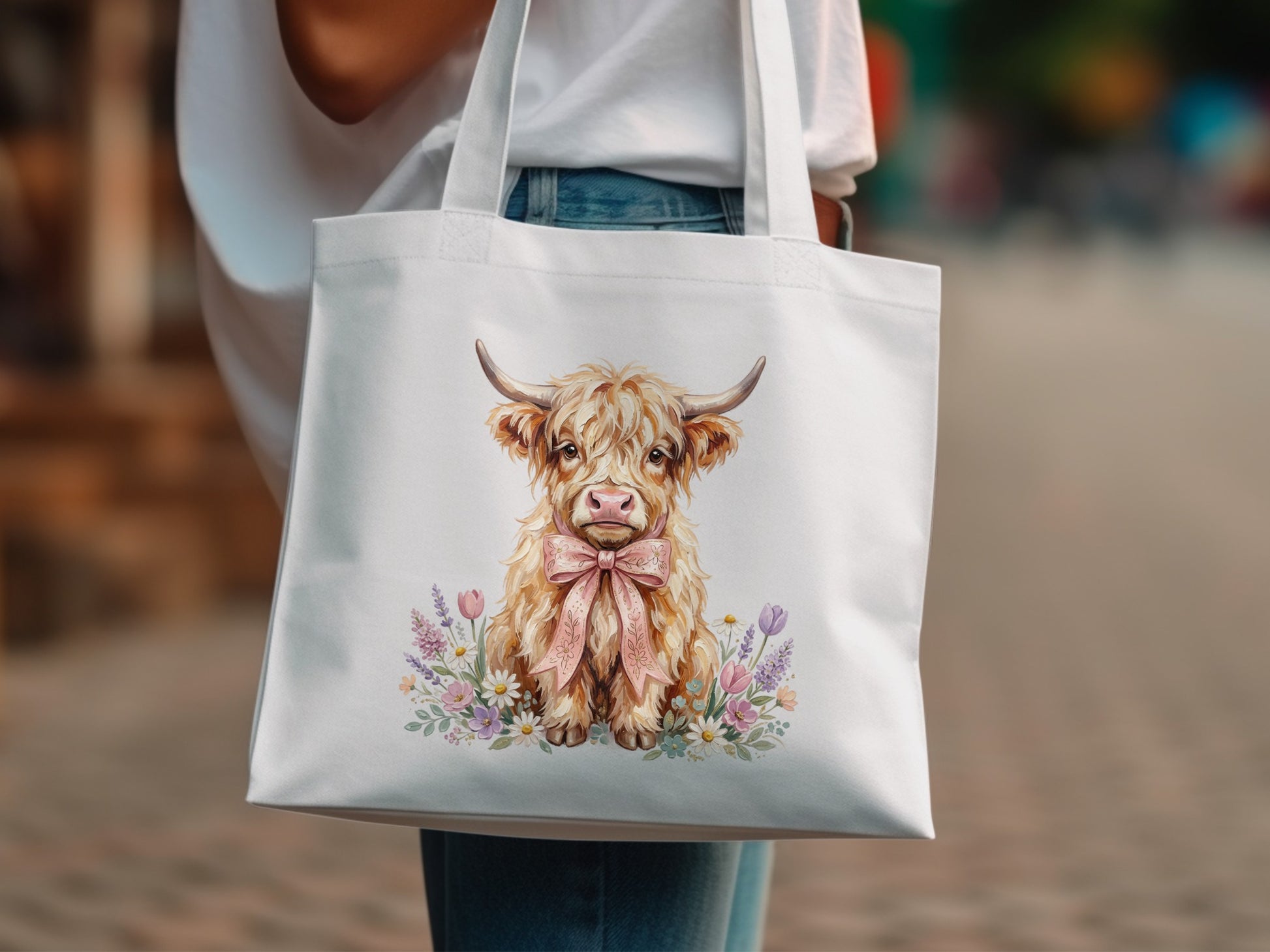 White tote bag with a watercolor Highland cow wearing a pink bow.