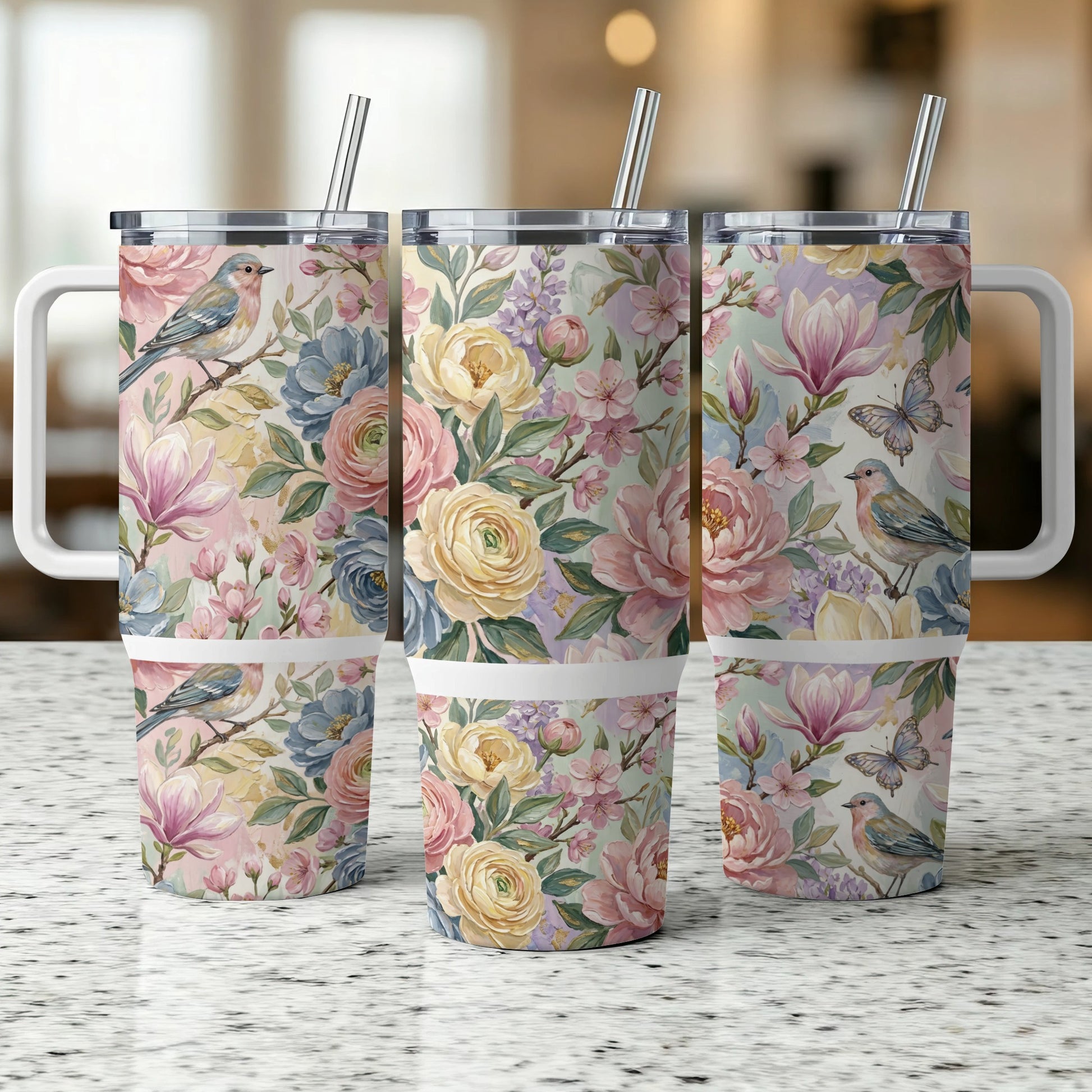 Three tumblers with floral and bird illustrations on a speckled countertop.