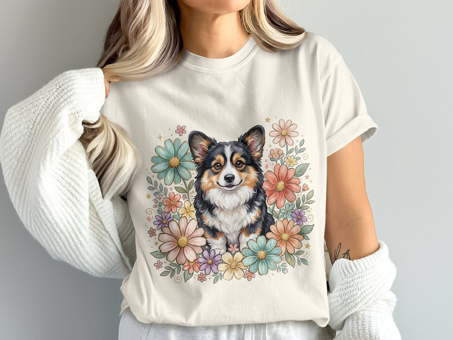 Tricolor corgi surrounded by pastel watercolor flowers on a cream t-shirt.
