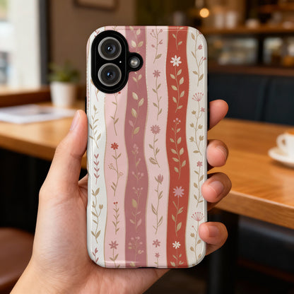 Floral stripe phone case held in hand with blurry cafe background.