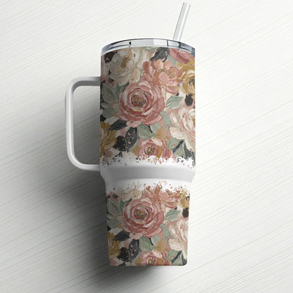 Floral patterned tumbler with handle and straw on white wooden surface.