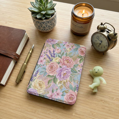 Floral patterned e-reader cover with accessories on a wooden desk.